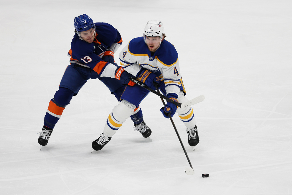 New York Islanders center Mathew Barzal (13) and Buffalo Sabres defenseman Bowen Byram (4) go after the puck during the first period of an NHL hockey game, Saturday, Jan. 24, 2026, in Elmont, N.Y. (AP Photo/Heather Khalifa)