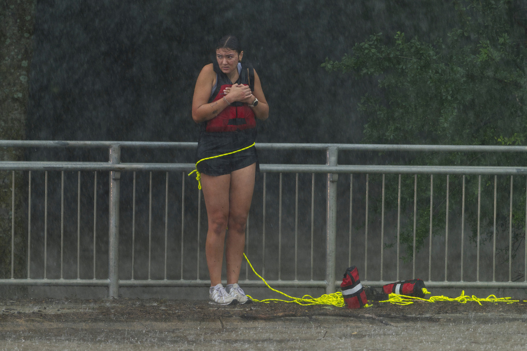 A woman stands on a sidewalk after being rescued from flood waters by members of the Boerne Fire Dept. on Wednesday, July 15, 2026, in Boerne, Texas. (AP Photo/Darren Abate)