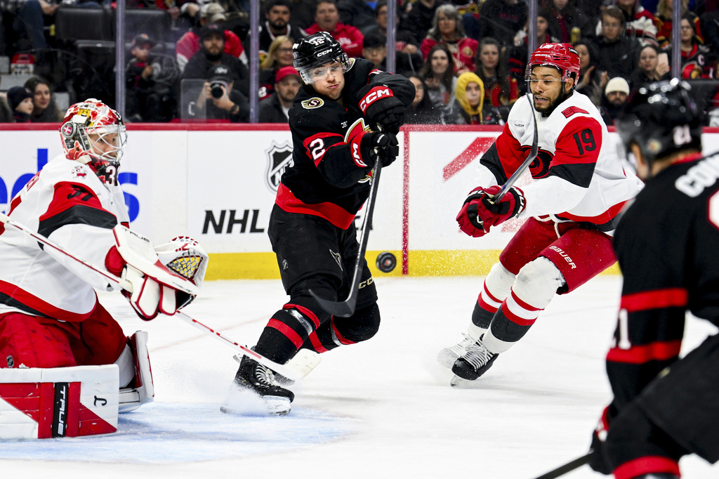 Ottawa Senators' Shane Pinto (12) tries pass to teammate Nick Cousins (21) in front of Carolina Hurricanes' goaltender Frederik Andersen (31) during the second period of an NHL hockey game in Ottawa, Ontario, on Sunday, April 5, 2026. (Spencer Colby/The Canadian Press via AP)