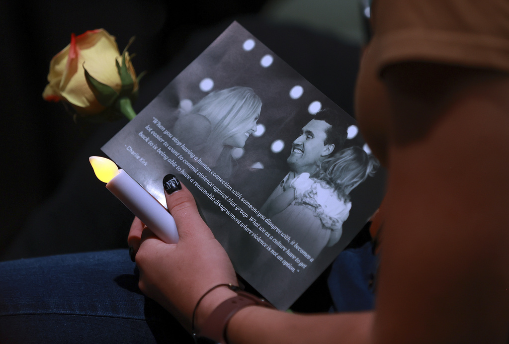 A woman holds a candle, flower and flyer during a Vigil for Unity at the UCCU Center at Utah Valley University in Orem on Friday, Sept. 19, 2025. Charlie Kirk, conservative activist and the founder and president of Turning Point USA, was fatally shot while answering questions at his American Comeback Tour at UVU on Sept. 10. (Kristin Murphy/The Deseret News via AP)