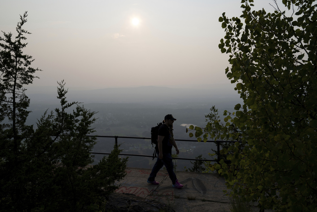 FILE - Keith Bergeron hikes along a ridge at the Mount Tom State Reservation as haze from wildfires is visible in Holyoke, Mass., Aug. 5, 2025. (Daniel Jacobi II/The Daily Hampshire Gazette via AP)
