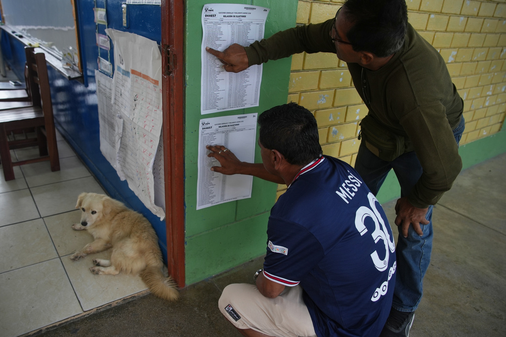 Voters check the rolls as voting in the general election resumes at polling stations affected by delays and logistical problems in Lima, Peru, Monday, April 13, 2026. (AP Photo/Guadalupe Pardo)