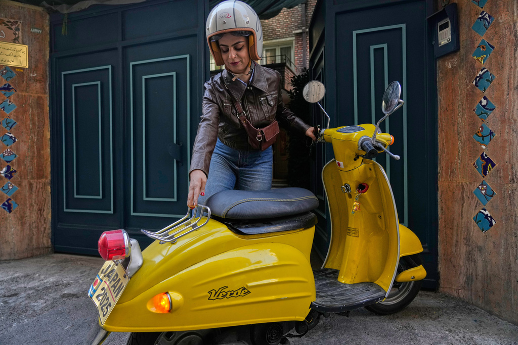 Merat Behnam parks her motorbike outside her cafe in downtown Tehran, Iran, Saturday, Nov. 1, 2025. (AP Photo/Vahid Salemi)