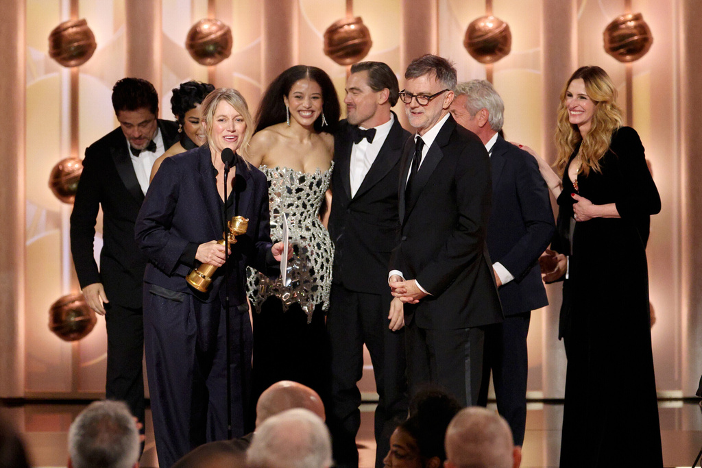This image released by CBS Broadcasting shows Sara Murphy, foreground left, appearing with writer-director Paul Thomas Anderson, foreground right, and other cast members, as well as presenter Julia Roberts, right, as they accept the award for best motion picture - musical or comedy for "One Battle After Another" during the 83rd Golden Globes on Sunday, Jan. 11, 2026, at the Beverly Hilton in Beverly Hills, Calif. (Kevork Djansezian/CBS Broadcasting via AP)