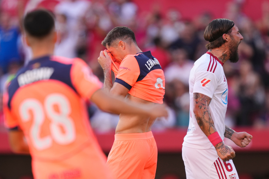 Barcelona's Robert Lewandowski, centre, reacts after missing a scoring chance during the Spanish La Liga soccer match between Sevilla and Barcelona at the Ramon Sanchez Pizjuan stadium in Seville, Spain, Sunday, Oct. 5, 2025. (AP Photo/Jose Breton)