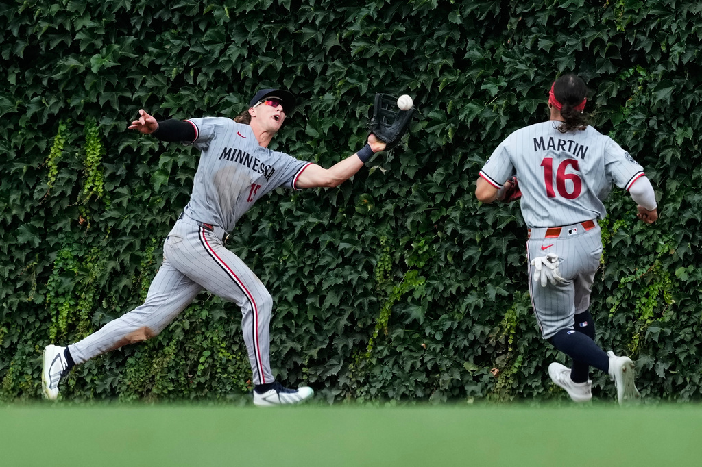 Minnesota Twins center fielder Luke Keaschall, left, can't make the play on a triple by Chicago Cubs' Dansby Swanson as Minnesota Twins right fielder Austin Martin looks on during the sixth inning of a baseball game in Chicago, Saturday, July 18, 2026. (AP Photo/Nam Y. Huh)