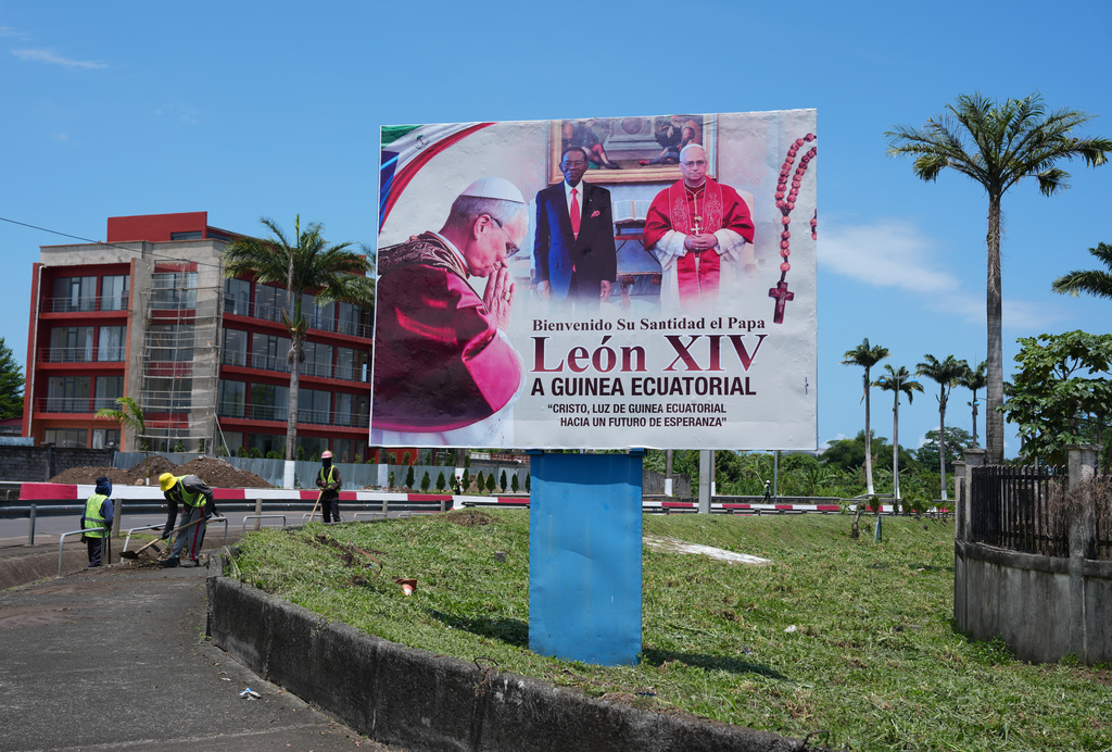 People work near a billboard featuring Pope Leo XIV, right, and Equatorial Guinea's President Teodoro Obiang Nguema Mbasogo, ahead of the Pope's visit in Malabo, Equatorial Guinea, Friday, April 17, 2026. (AP Photo/Misper Apawu)
