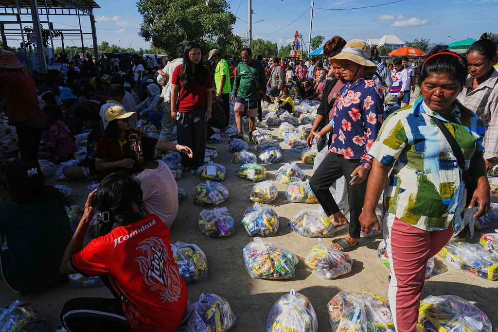 Evacuees wait to receive donation from local charity as they take refuge in Banteay Menchey provincial town, Cambodia, Saturday, Dec. 13, 2025, after fleeing homes following fighting between Thailand and Cambodia. (AP Photo/Heng Sinith)