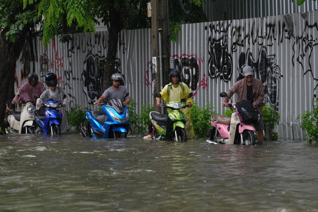 Men push motorcycles as they wade through floodwaters after heavy rain in Bangkok, Thailand Saturday, Sept. 26, 2026. (AP Photo/Sakchai Lalit)