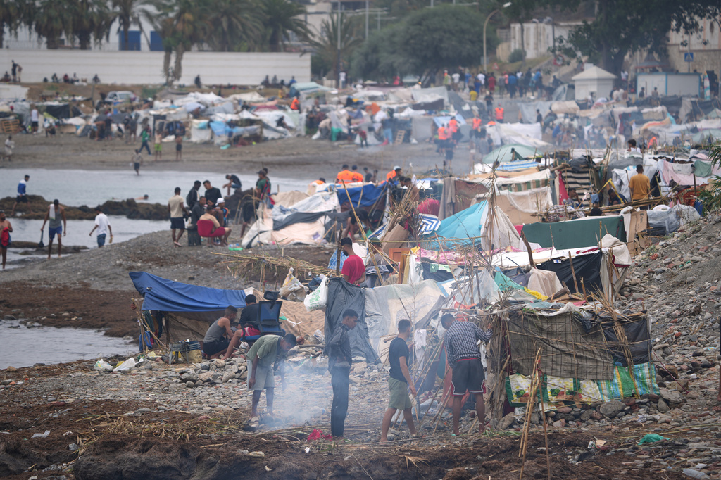 Migrants stand near their tents at El Trampolín beach in the Spanish exclave of Ceuta, Wednesday, Sept. 2, 2026. (AP Photo/Francis González)