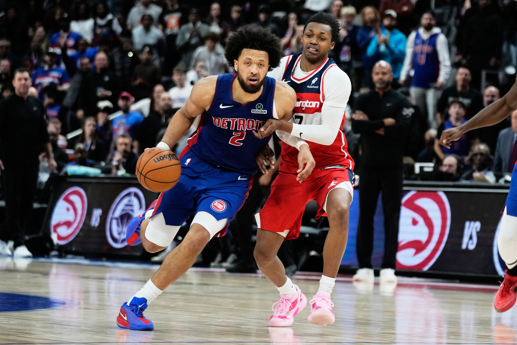 Detroit Pistons guard Cade Cunningham, left, drives against Washington Wizards guard Bub Carrington during overtime in an NBA basketball game Monday, Nov. 10, 2025, in Detroit. (AP Photo/Ryan Sun)