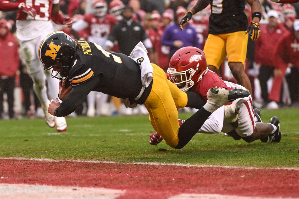 Missouri quarterback Beau Pribula, left, dives past Arkansas defensive back Shakur Smalls to score a touchdown during the first half of an NCAA college football game, Saturday, Nov. 29, 2025, in Fayetteville, Ark. (AP Photo/Michael Woods)