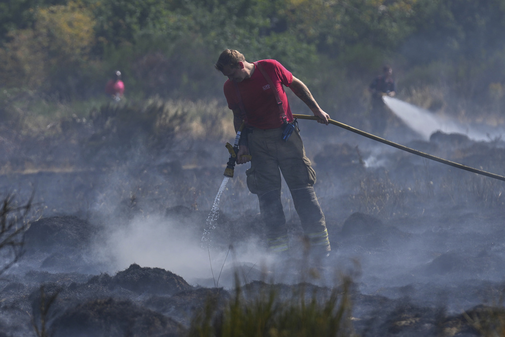 Members of the London Fire Brigade tackle a wildfire on Wanstead Flats in London, Tuesday, Aug. 12, 2025. (AP Photo/Joanna Chan)