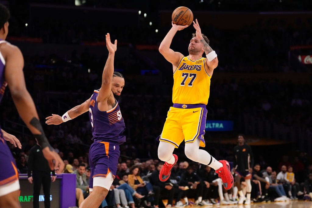 Los Angeles Lakers guard Luka Doncic, right, shoots as Phoenix Suns forward Dillon Brooks defends during the first half of an NBA basketball game Monday, Dec. 1, 2025, in Los Angeles. (AP Photo/Mark J. Terrill)