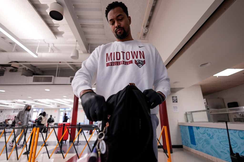 Athletic director Rod Hill checks a student's bag at Midtown High School, Friday, March 6, 2026, in Atlanta. (AP Photo/Mike Stewart)