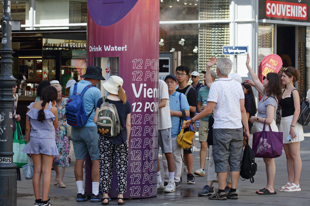People line up to refill their water bottles on a hot summer day in the city center of Vienna, Austria, Saturday, June 27, 2026. (AP Photo/Heinz-Peter Bader)
