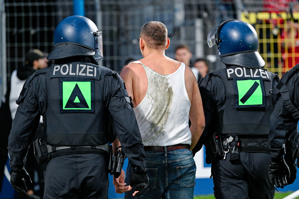 An SV Waldhof Mannheim supporter is escorted away off the pitch by police officers during the Germany Cup soccer match between SV Waldhof Mannheim and 1. FC Kaiserslautern, Friday, Aug. 21, 2026, in Mannheim, Germany. (Uwe Anspach/dpa via AP)