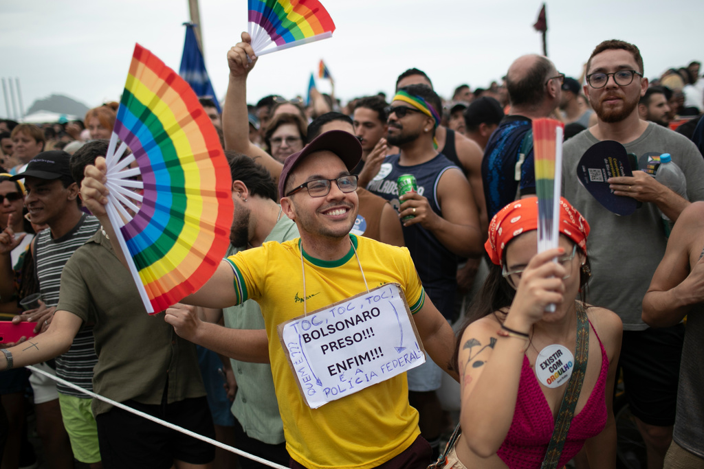 A man wears a sign that reads in Portuguese, "Bolsonaro arrested! Finally!" during the annual Rio Pride parade along Copacabana Beach in Rio de Janeiro, Sunday, Nov. 23, 2025. (AP Photo/Bruna Prado)