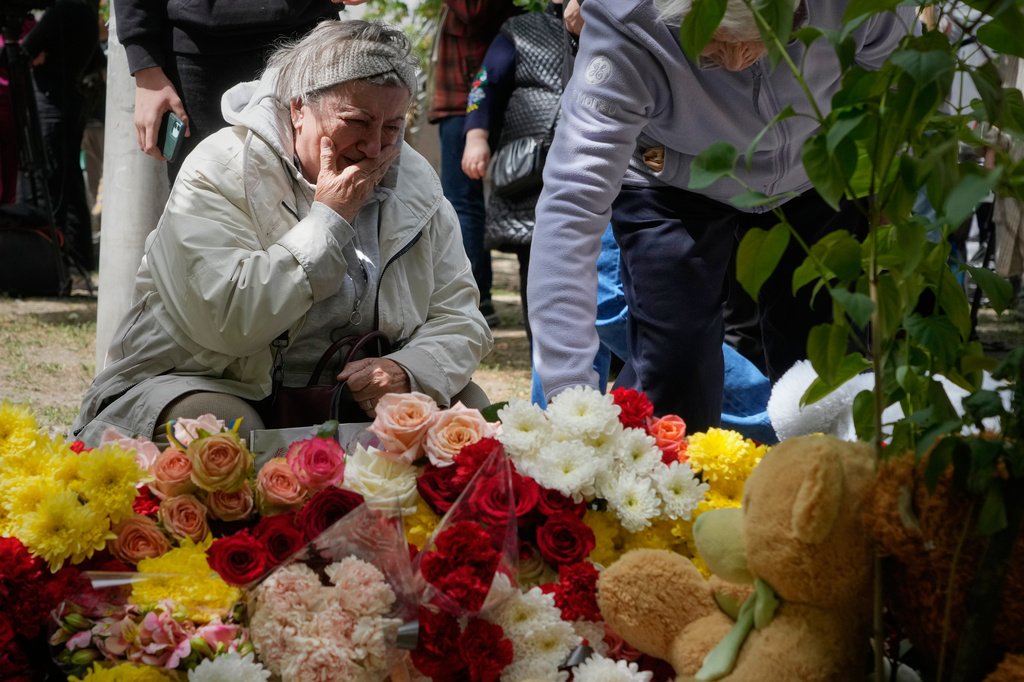 People lay flowers in front of a house heavily damaged after a Russian strike on residential neighbourhood in Kyiv, Ukraine, on Friday, May 15, 2026. (AP Photo/Efrem Lukatsky)