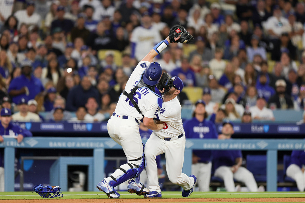 Los Angeles Dodgers catcher Will Smith, left, collides with third baseman Max Muncy, right, while catching a popout by Chicago Cubs' Ian Happ during the fourth inning of a baseball game Friday, April 24, 2026, in Los Angeles. (AP Photo/Ryan Sun)