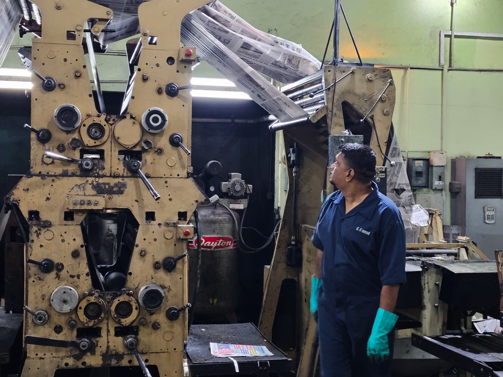 A worker looks at the impression of the last edition of Guyana's Stabroek News newspaper as it closes after 39 years in Georgetown, Guyana, Saturday, March 14, 2026. (AP Photo/Bert Wilkinson)