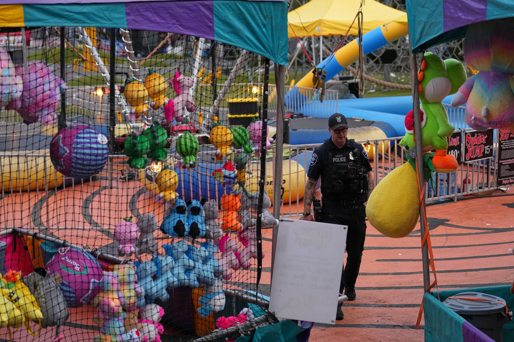 A Seattle Police officer walks through tents with colorful toys at the scene of a shooting at Seattle Center during the Bite of Seattle food festival Sunday, July 26, 2026, in Seattle. (AP Photo/Lindsey Wasson)