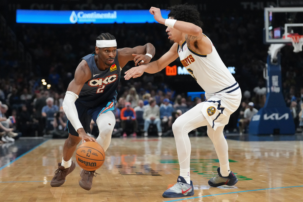 Oklahoma City Thunder guard Shai Gilgeous-Alexander, left, drives past Denver Nuggets guard Julian Strawther, right, during the second half of an NBA basketball game, Friday, Feb. 27, 2026, in Oklahoma City. (AP Photo/Kyle Phillips)