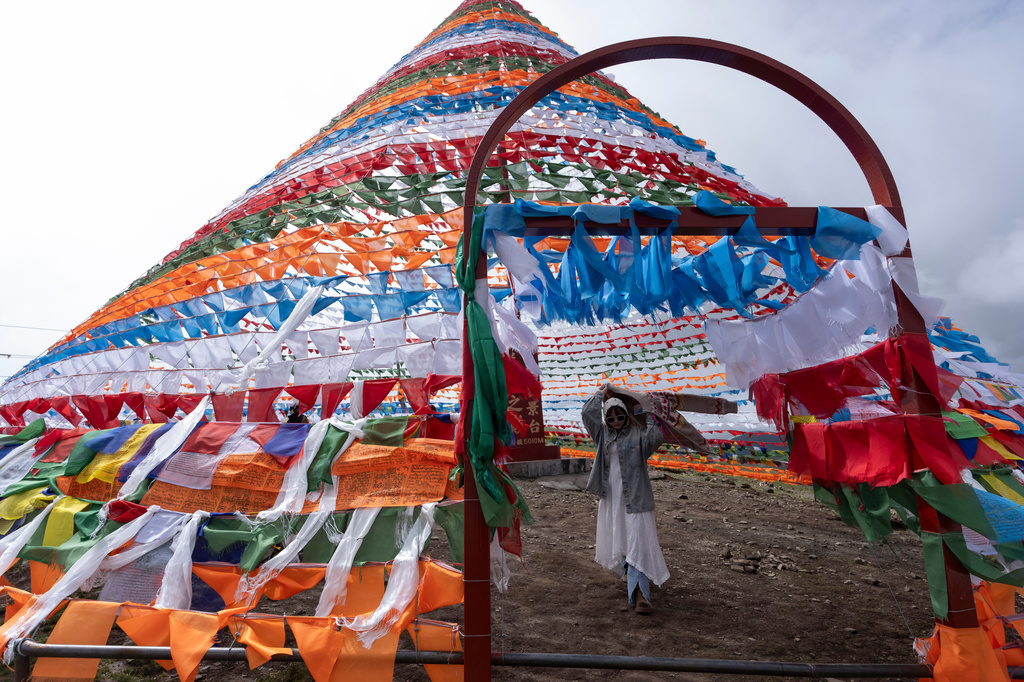 A tourist walks inside prayer flags near Yamdrok Lake in western China's Tibet Autonomous Region on Thursday, July 23, 2026, as seen during a government organized visit for foreign journalists. (AP Photo/Ng Han Guan)