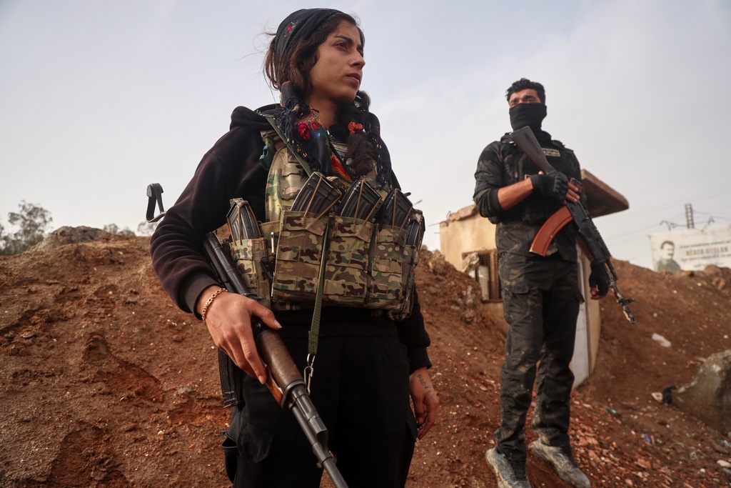 Kurdish-led Syrian Democratic Forces (SDF) combatants look on as a contingent of Syria's Interior Ministry security forces arrive to implement an agreement aimed at stabilizing a ceasefire in al-Hassakeh, eastern Syria, Monday, Feb. 2, 2026. (AP Photo/Baderkhan Ahmad)
