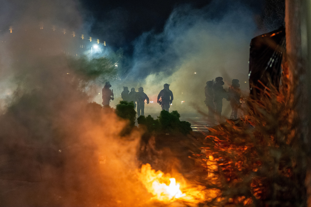 Federal immigration officers are seen outside Bishop Whipple Federal Building after tear gas was deployed Monday, Jan. 12, 2026, in Minneapolis. (AP Photo/Jen Golbeck)