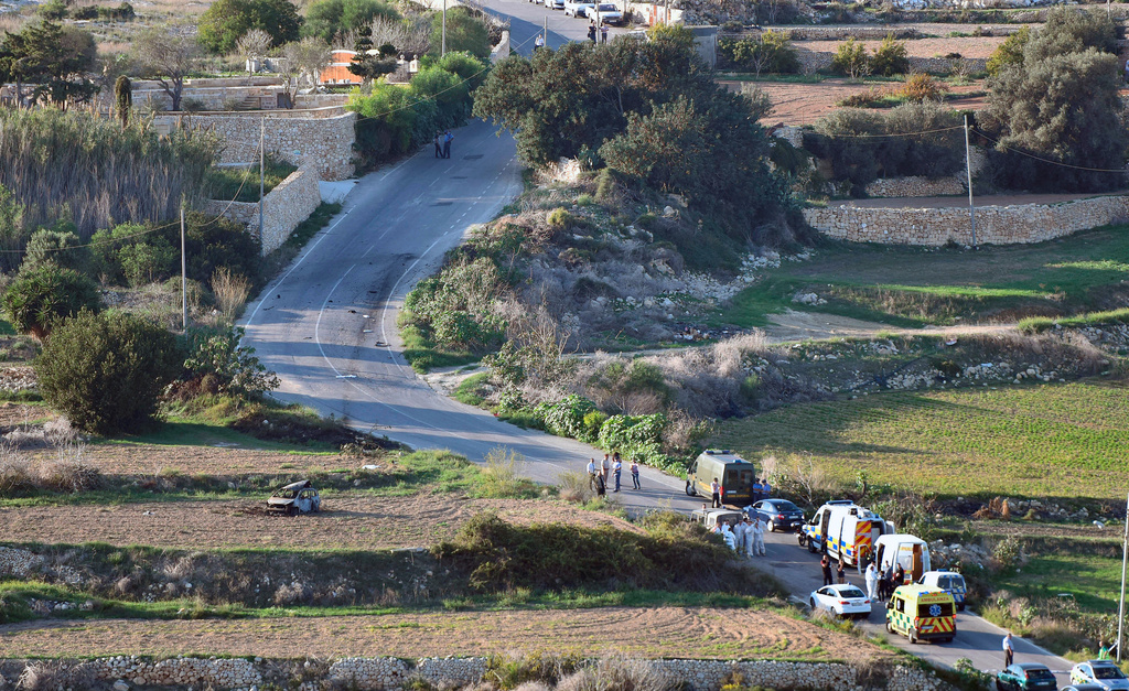 FILE - An ambulance and police vehicles are parked along the road where a car bomb exploded killing investigative journalist Daphne Caruana Galizia, in the town of Mosta, Malta, Oct. 16, 2017. (AP Photo/Rene Rossignaud, File)