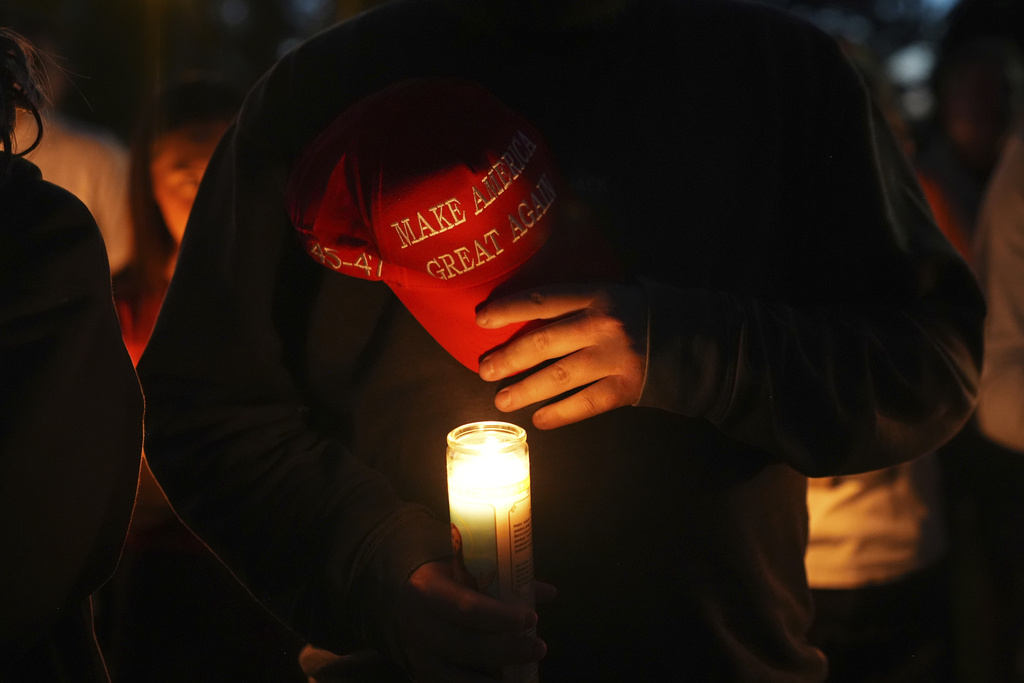 Alex Thomson holds a "Make America Great Again" hat during a vigil for Charlie Kirk on Friday, Sept. 12, 2025, in Provo, Utah. (AP Photo/Lindsey Wasson)
