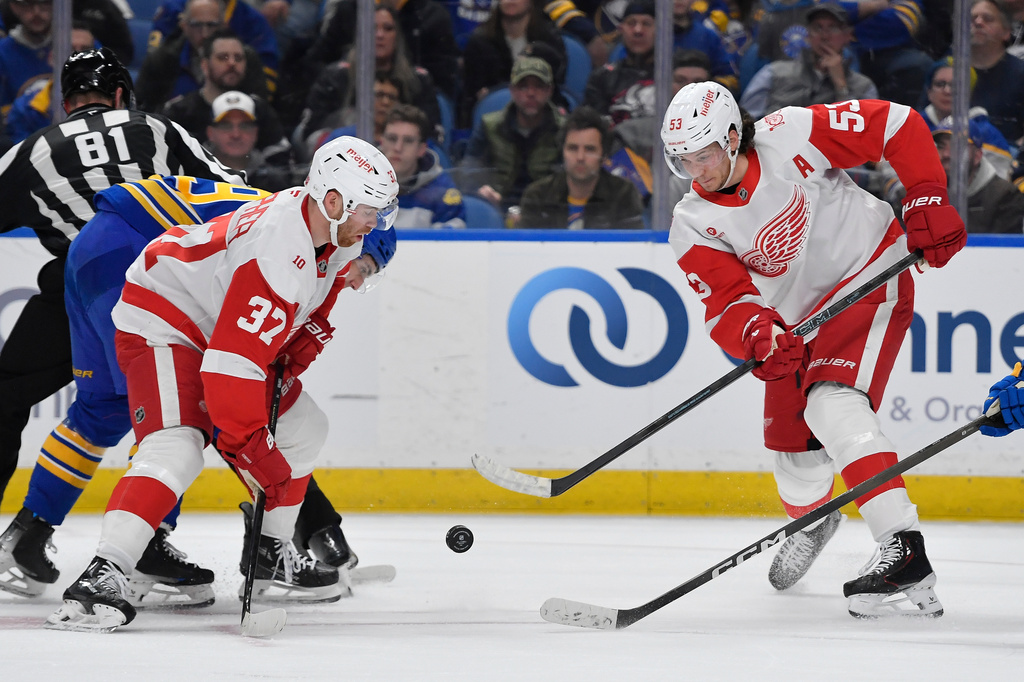 Detroit Red Wings defenseman Moritz Seider, right, clears the puck as left wing J.T. Compher looks on during the first period of an NHL hockey game against the Buffalo Sabres, Friday, March 27, 2026, in Buffalo, N.Y. (AP Photo/Adrian Kraus)