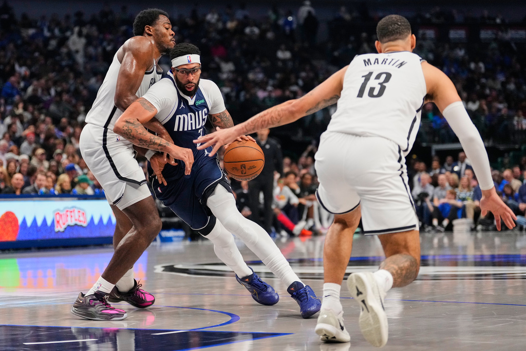 Dallas Mavericks forward Anthony Davis, center, works for a shot attempt against Brooklyn Nets' Day'Ron Sharpe, left, and Tyrese Martin (13) in the first half of an NBA basketball game in Dallas, Friday, Dec. 12, 2025. (AP Photo/Tony Gutierrez)