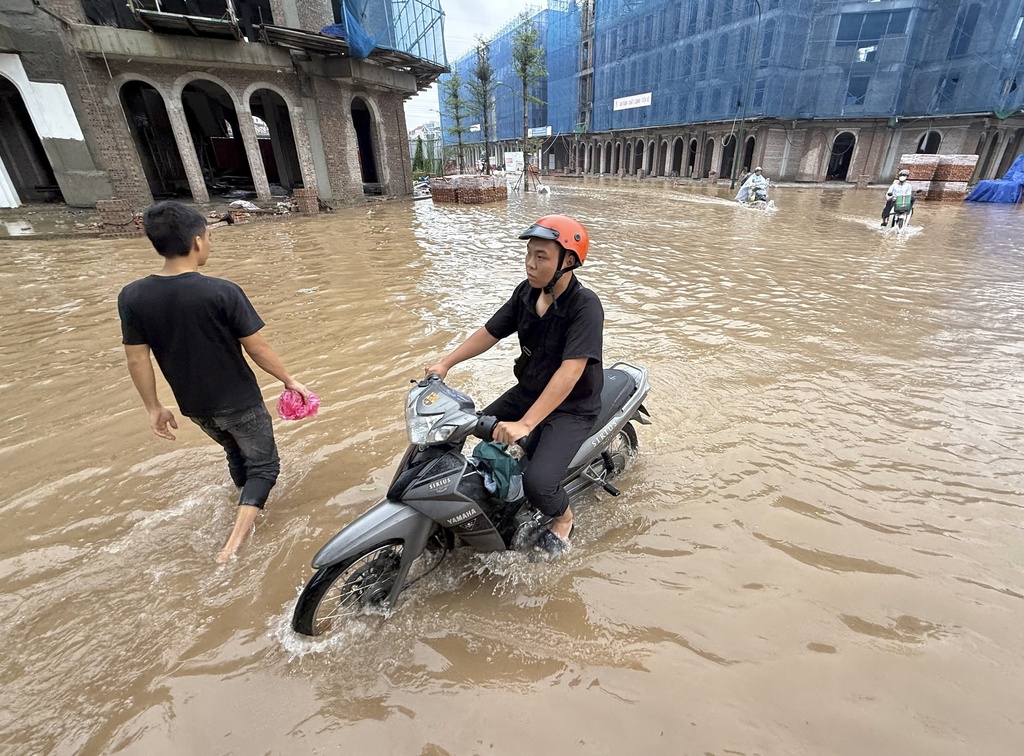 People ride motorcycles on a flooded street in the aftermath of Typhoon Kajiki in Hanoi, Vietnam, Wednesday, Aug. 27, 2025. (AP Photo/Hau Dinh)