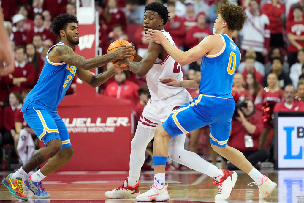 UCLA guard Donovan Dent (2) and UCLA guard Trent Perry (0) attempt to steal the ball from Wisconsin guard John Blackwell, center, during the second half of an NCAA college basketball game Tuesday, Jan. 6, 2026, in Madison, Wis. (AP Photo/Kayla Wolf)