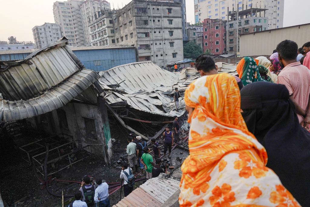 People look at the charred remains of a gas-lighter manufacturing factory in Keraniganj on the outskirts of Dhaka, Bangladesh, Saturday, April 4, 2026. (AP Photo/MD. Samsul Islam Hady)