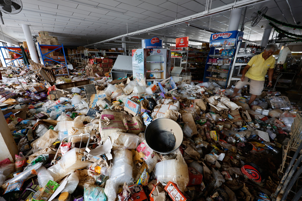 Somsak Remsringam, owner of the convenience shop, looks at the damaged contents after floods in Songkhla province, southern Thailand, Friday, Nov. 28, 2025. (AP Photo/Sarot Meksophawannakul)