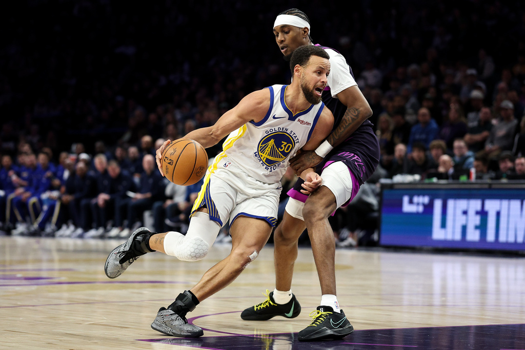 Golden State Warriors guard Stephen Curry (30) works around Minnesota Timberwolves forward Jaden McDaniels, top, during the first half of an NBA basketball game Sunday, Jan. 25, 2026, in Minneapolis. (AP Photo/Matt Krohn)