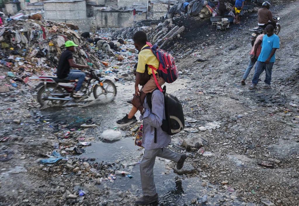 A man carries a child on his shoulders to take him to school in the Petion-Ville neighborhood of in Port-au-Prince, Haiti, Monday, March 2, 2026. (AP Photo/Odelyn Joseph)