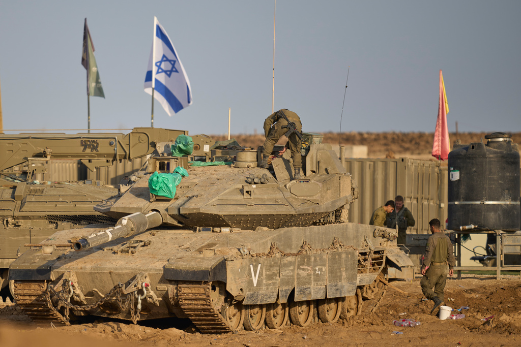 Israeli soldiers work on tanks at a staging area on the border with Gaza Strip, in southern Israel, Tuesday, Nov. 18, 2025. (AP Photo/Ohad Zwigenberg)