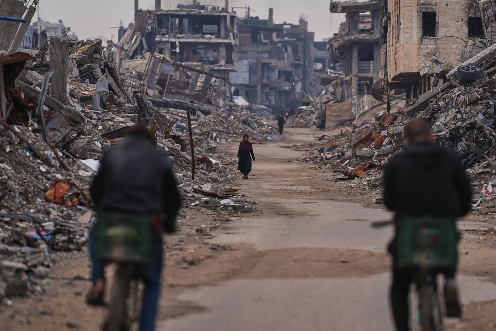 A Palestinian woman walks along a street surrounded by buildings destroyed during Israeli air and ground operations in the Sheikh Radwan neighborhood, in Gaza City, Tuesday, Dec. 30, 2025. (AP Photo/Abdel Kareem Hana)
