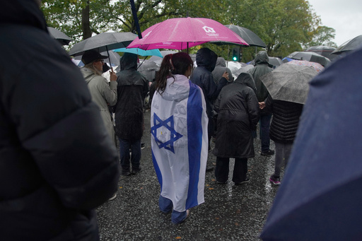 A woman wears the flag of Israel wrapped over her back as she attends a vigil for the victims of the attack on at Heaton Park Hebrew Congregation synagogue, in Crumpsall, Manchester, England, Friday, Oct. 3, 2025. (AP Photo/Ian Hodgson) A woman wears the flag of Israel wrapped over her back as she attends a vigil for the victims of the attack on at Heaton Park Hebrew Congregation synagogue, in Crumpsall, Manchester, England, Friday, Oct. 3, 2025. (AP Photo/Ian Hodgson)