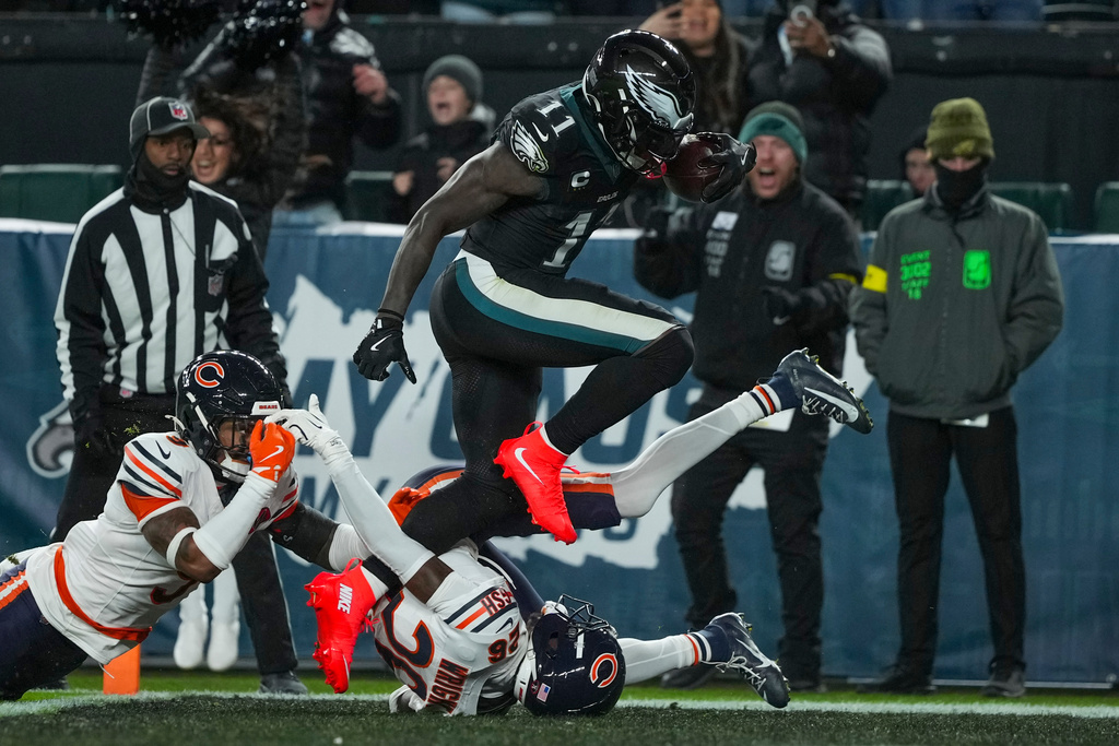 Philadelphia Eagles wide receiver A.J. Brown (11) jumps over Chicago Bears cornerback Nahshon Wright (26) to score a touchdown during the second half of an NFL football game, Friday, Nov. 28, 2025, in Philadelphia. (AP Photo/Matt Slocum)