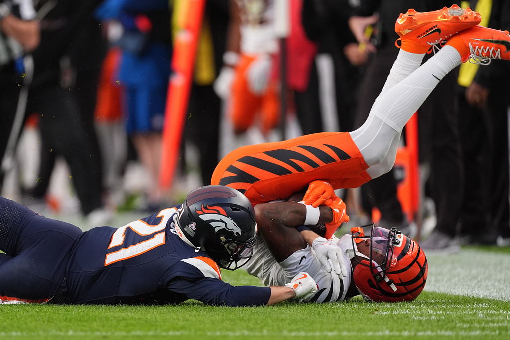 Cincinnati Bengals wide receiver Tee Higgins (5) catches a pass against Denver Broncos cornerback Riley Moss (21) during the first half of an NFL football game Monday, Sept. 29, 2025, in Denver. (AP Photo/David Zalubowski)