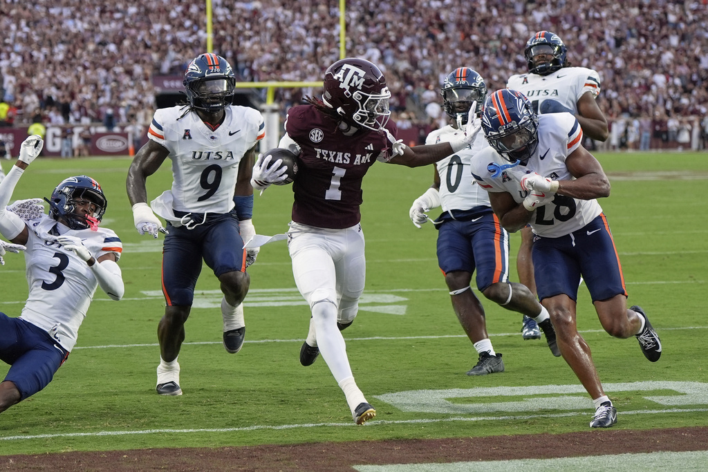Texas A&M's Mario Craver (1) scores a touchdown after catching a pass as UTSA cornerback KK Meier (28) defends during the first half of an NCAA college football game Saturday, Aug. 30, 2025, in College Station, Texas. (AP Photo/David J. Phillip)