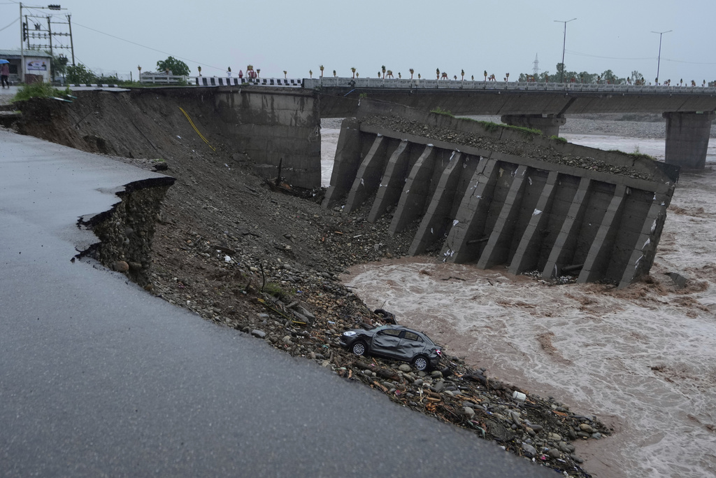 People looks at the damaged bridge over the swelling Tawi River in Jammu, India, Wednesday, Aug. 27, 2025. (AP Photo/Channi Anand)
