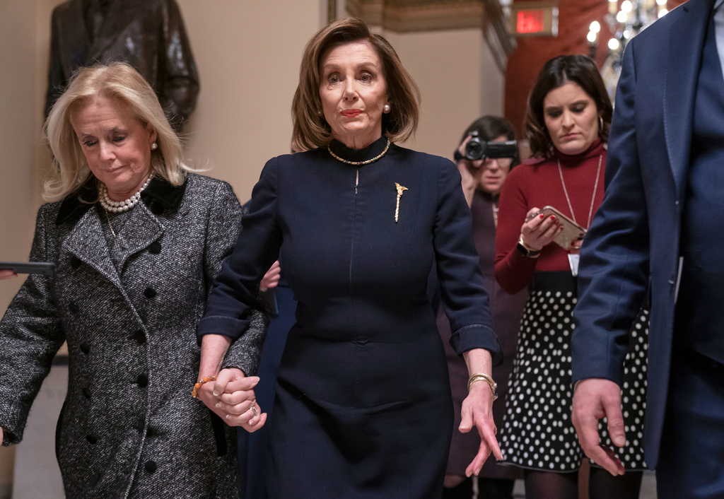 FILE - Speaker of the House Nancy Pelosi, D-Calif., holds hands with Rep. Debbie Dingell, D-Mich., as they walk to the chamber where the Democratic-controlled House of Representatives begins a day of debate on the impeachments charges against President Donald Trump for abuse of power and obstruction of Congress, at the Capitol in Washington, Dec. 18, 2019. (AP Photo/J. Scott Applewhite, File)