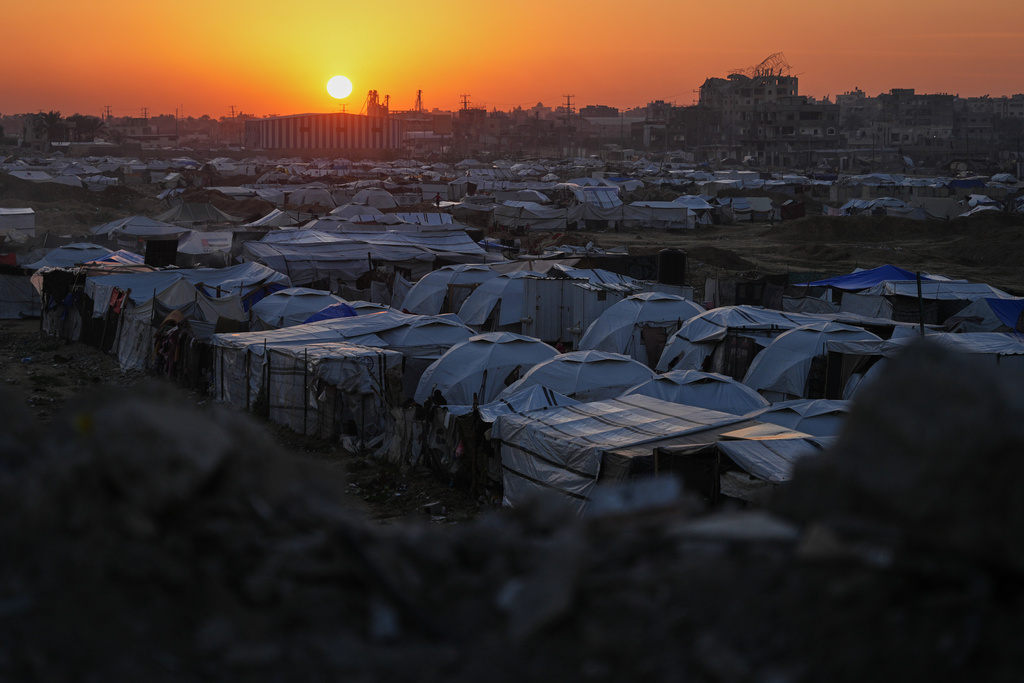 The sun sets behind a makeshift tent camp for displaced Palestinians set up in an area of al-Bureij camp, in the central Gaza Strip, Wednesday, Dec. 24, 2025. (AP Photo/Abdel Kareem Hana)