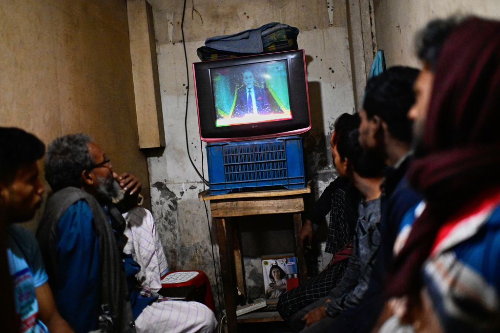 People watch Bangladesh's Chief Election Commissioner A.M.M. Nasir Uddin's address to the nation on a television, in Dhaka, Bangladesh, Thursday, Dec. 11, 2025. (AP Photo/Mahmud Hossain Opu)